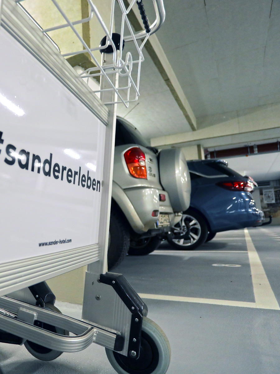 Die Tiefgarage mit einem Gepäcktrolley und zwei Fahrzeugen im Hintergrund